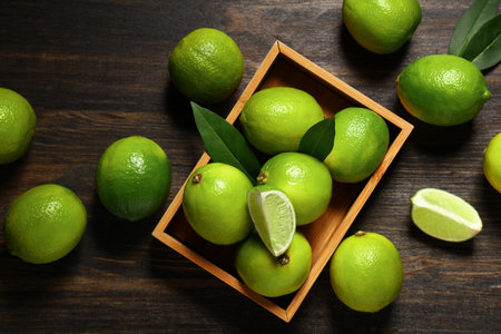 Box with fresh ripe limes on wooden backgroundの写真素材