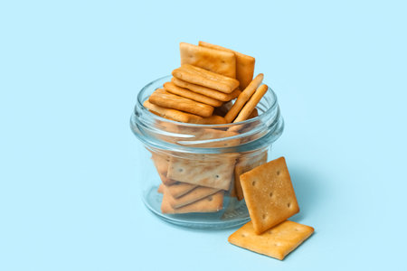 Glass jar with tasty crackers on blue background, closeupの写真素材
