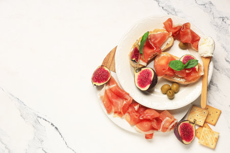 Plate of bread slices with prosciutto and fresh fig on white backgroundの写真素材