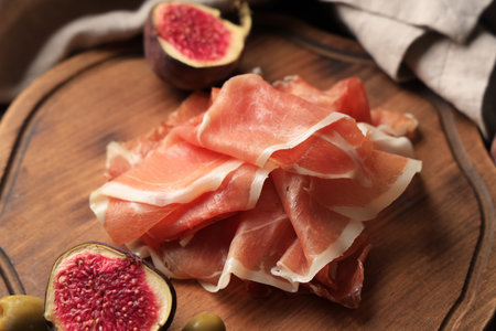 Delicious prosciutto slices with fresh fig on wooden board, closeupの写真素材
