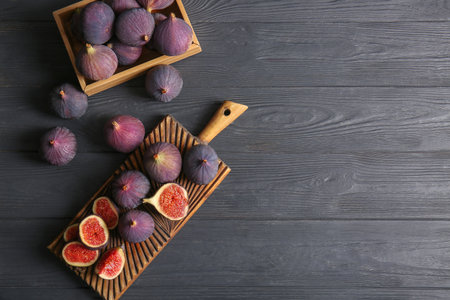Cutting board and box with fresh ripe figs on black wooden backgroundの写真素材