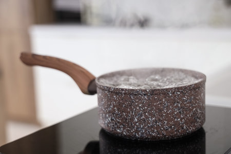 Saucepan with boiling water on mini stove in kitchen, closeupの写真素材