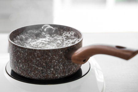 Saucepan with boiling water on stove in kitchen, closeupの写真素材