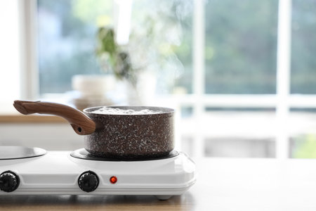 Saucepan with boiling water on stove in kitchenの写真素材
