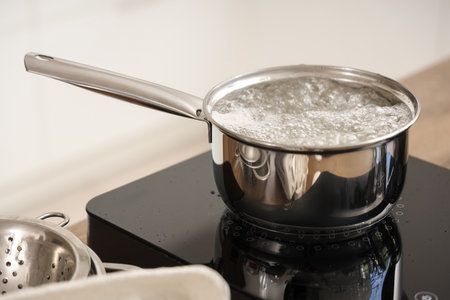 Saucepan with boiling water on mini stove in kitchen, closeupの写真素材
