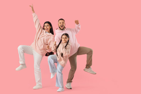 Happy parents with their little daughter dancing on pink backgroundの写真素材