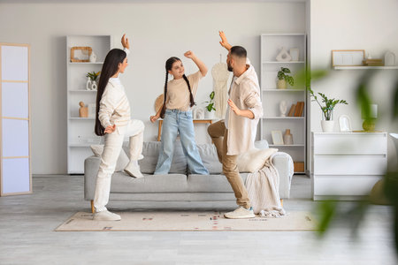 Cute little girl with her parents dancing at homeの写真素材