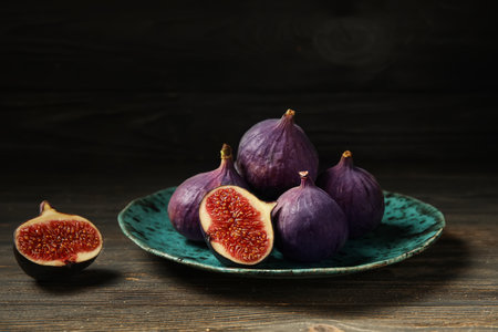 Plate with fresh ripe figs on black wooden table, closeupの写真素材