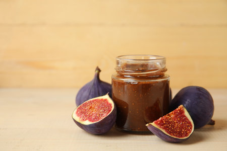 Jar of sweet fig jam on beige wooden table, closeupの写真素材