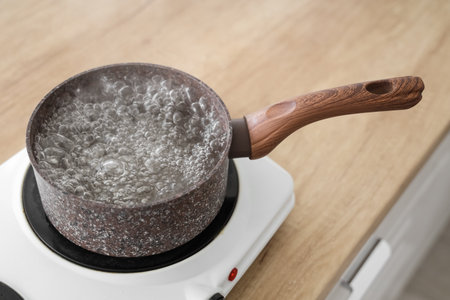 Saucepan with boiling water on stove in kitchen, closeupの写真素材