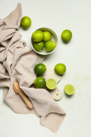 Bowl and cutting board with fresh ripe limes on white backgroundの写真素材