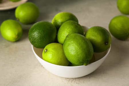 Bowl with fresh ripe limes on grunge background, closeupの写真素材