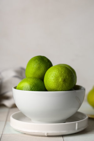 Bowl with fresh ripe limes on white tile tableの写真素材