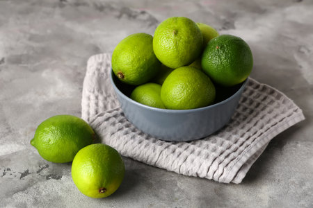 Bowl with fresh ripe limes on gray background, closeupの写真素材