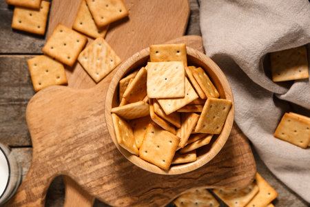 Composition with bowl of tasty crackers on gray wooden background, closeupの写真素材