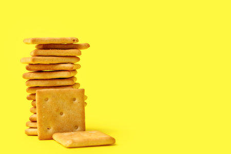 Stack of tasty crackers on yellow background, closeupの写真素材