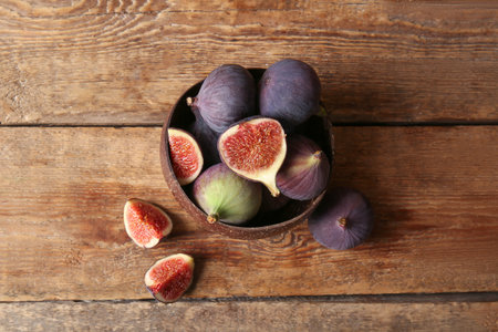 Bowl with fresh ripe figs on wooden backgroundの写真素材