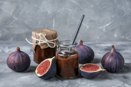 Jars of fig jam with spoon on gray grunge backgroundの写真素材