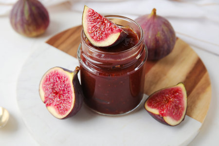 Board with jar of sweet fig jam on marble backgroundの写真素材