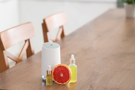 Air humidifier with essential oils and grapefruit on table in kitchen, closeupの写真素材