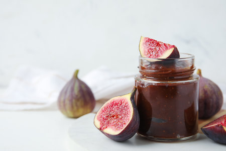 Board with jar of sweet fig jam on marble backgroundの写真素材