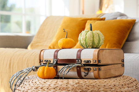 Suitcase with skeleton hands and Halloween pumpkins on pouf in living roomの写真素材