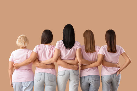 Group of beautiful women hugging on beige background, back view. Feminism conceptの写真素材