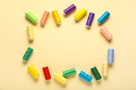 Frame made of colorful thread spools on beige backgroundの写真素材