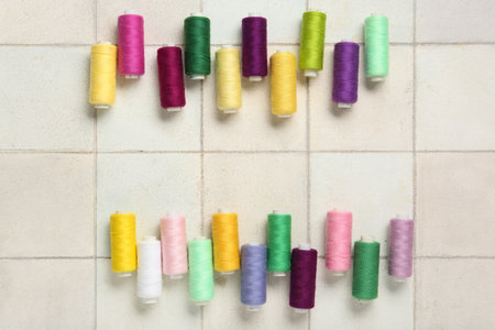 Colorful thread spools on white tile backgroundの写真素材