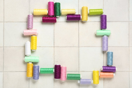 Frame made of colorful thread spools on white tile backgroundの写真素材