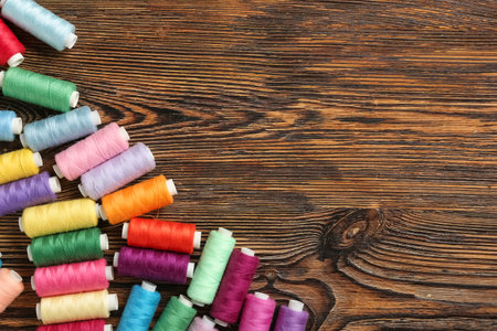 Colorful thread spools on wooden background