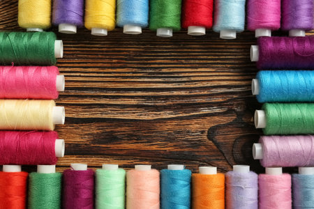 Frame made of colorful thread spools on wooden backgroundの写真素材