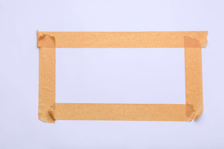 Frame made of brown masking tape strips on white backgroundの写真素材
