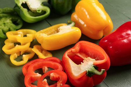 Fresh colorful bell peppers on green wooden background, closeupの写真素材