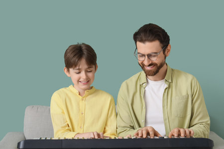 Private music teacher giving synthesizer lessons to boy on green backgroundの写真素材