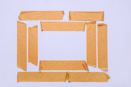 Frame made of brown masking tape strips on white backgroundの写真素材