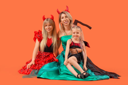 Happy girls with their grandmother dressed for Halloween sitting on orange backgroundの写真素材