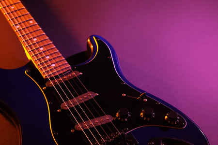 Modern electric guitar on purple backgroundの写真素材