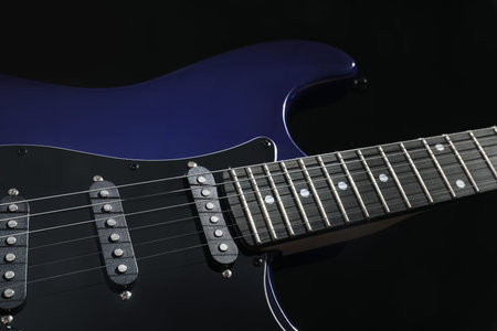 Modern electric guitar on black background, closeup