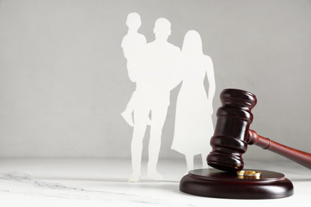 Judge's gavel with figures of family and rings on white backgroundの写真素材
