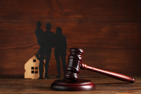 Judge's gavel with figures of family and house on brown wooden backgroundの写真素材