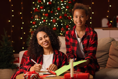 African-American mother and her daughter making greeting cards at home on Christmas Eveの写真素材
