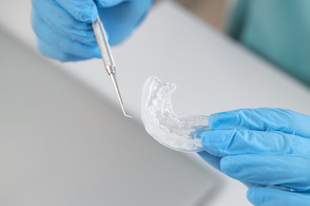 Female dentist's hands with occlusal splint and tool in clinic, closeupの写真素材