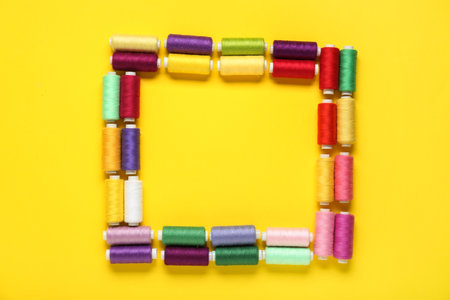 Frame made of colorful thread spools on yellow backgroundの写真素材