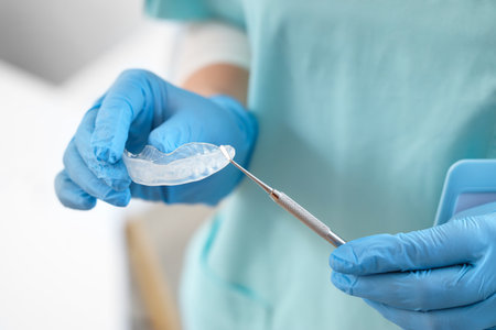 Female dentist with occlusal splint and tool in clinic, closeupの写真素材