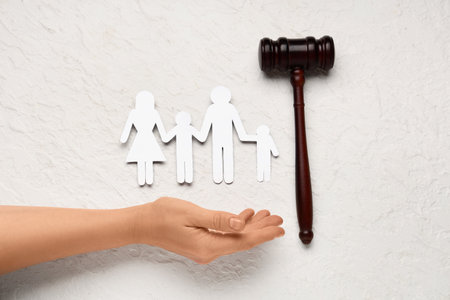Female hand with judge's gavel and figures of family on grunge white backgroundの写真素材