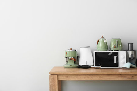 Different modern household appliances on wooden table against white wallの写真素材