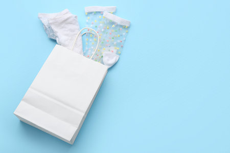 Paper shopping bag with stylish white lingerie and socks on blue backgroundの写真素材