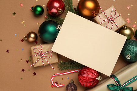 Blank card with Christmas balls, gift boxes, candy cane and fir branches on brown backgroundの写真素材