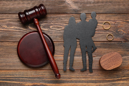 Judge's gavel with figures of family and rings on brown wooden backgroundの写真素材